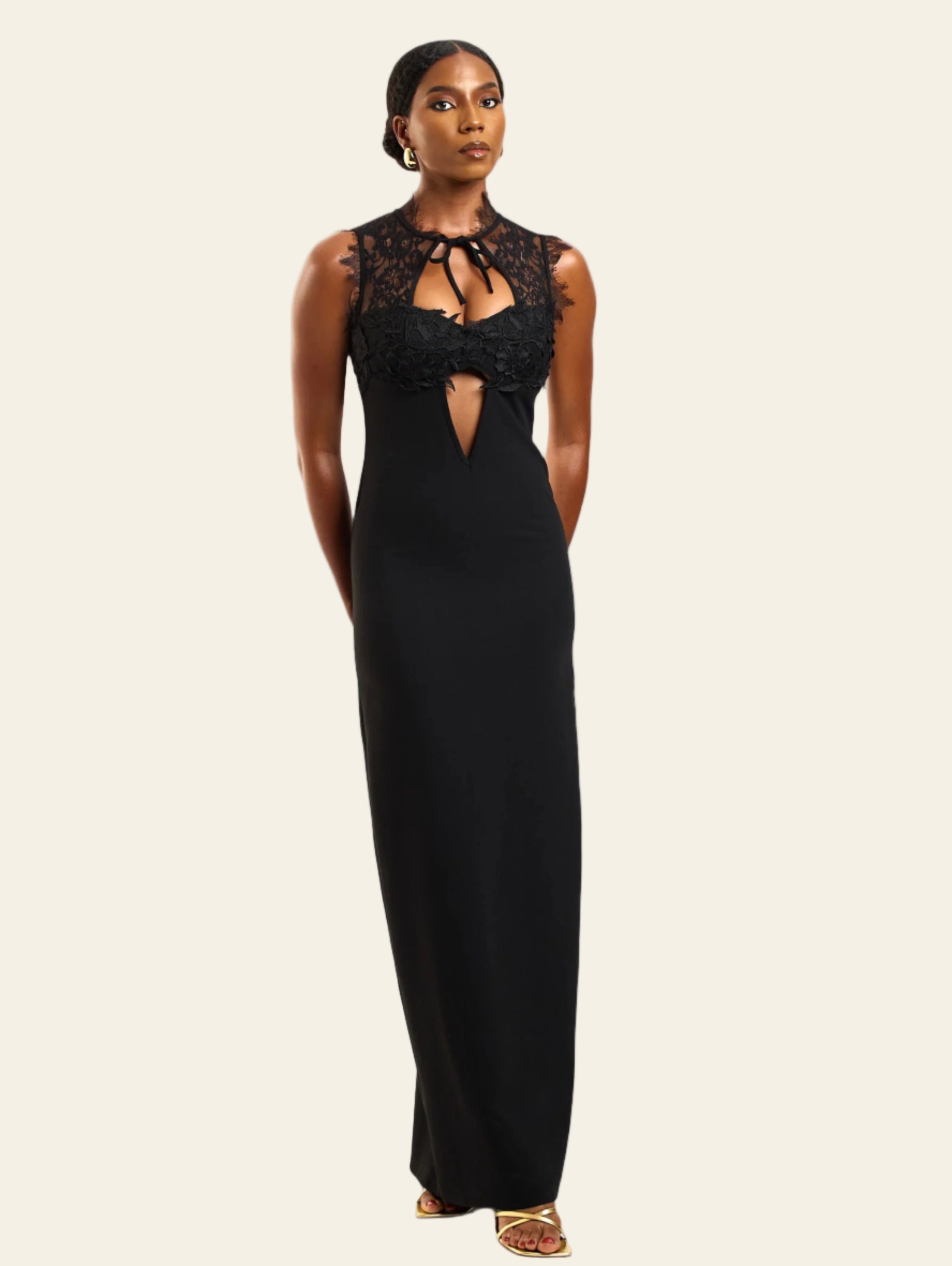Woman wearing a black evening gown with lace detailing on a white background