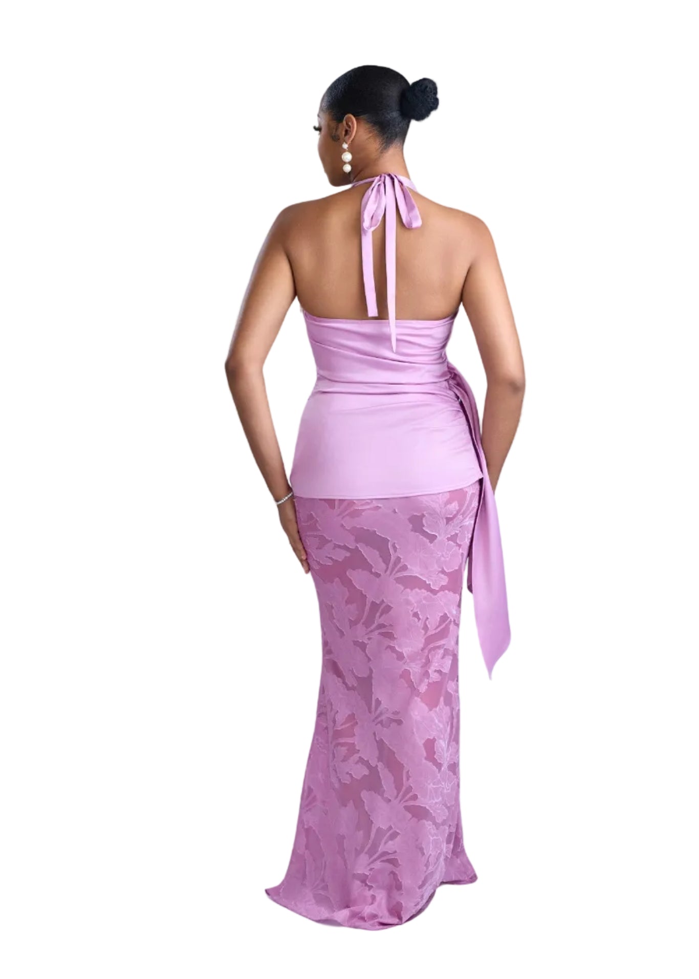 Woman wearing a pink dress with a lace overlay on a light background
