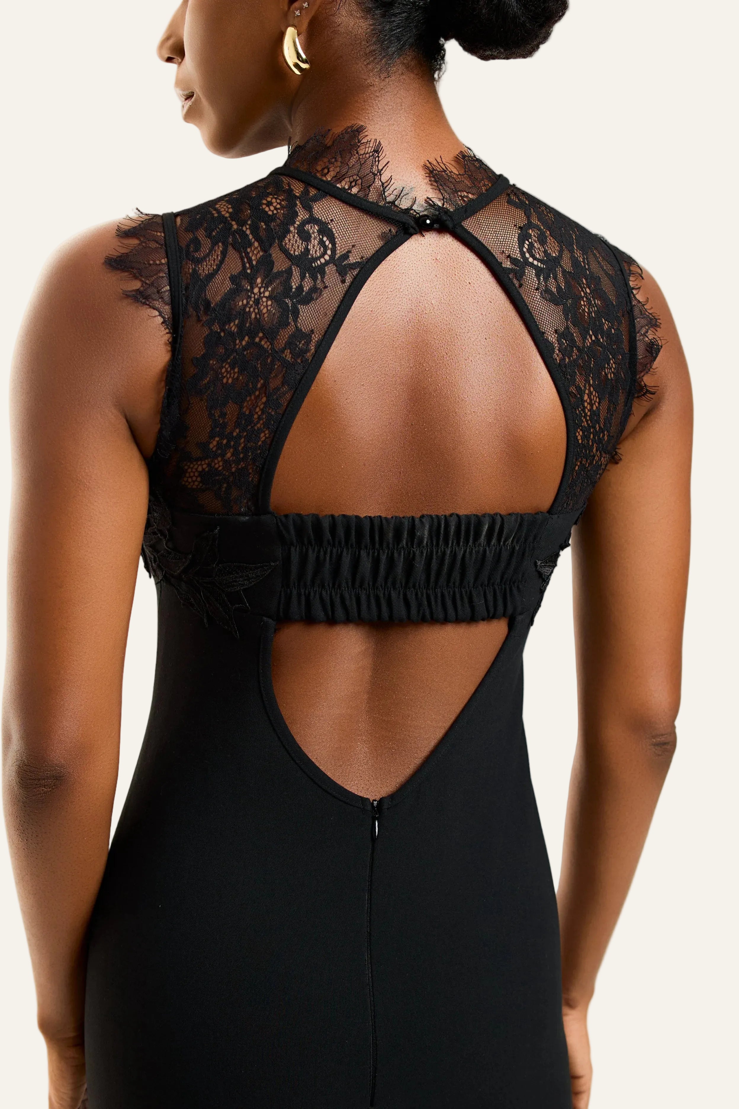 Black lace dress with open back on a model against a white background